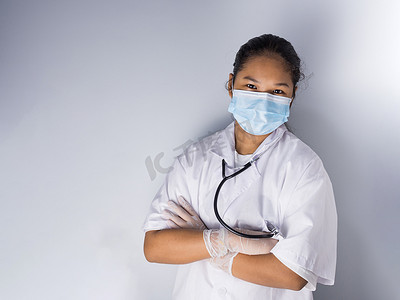 一位戴着口罩站在白色背景上的女医生的工作室肖像他的脸上有淡淡的光。