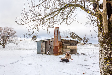 在雪原和古老的乡村谷仓中放松的女人