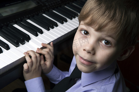 坐在钢琴前微笑的小男孩