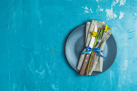 空的蓝盘子和餐巾纸上放着水仙花的餐具