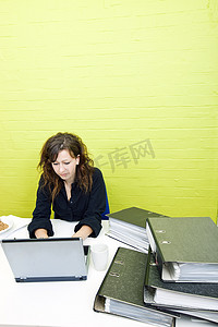 在办公桌前用笔记本电脑工作的白人年轻女性