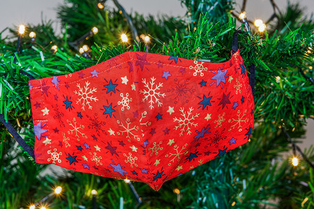 圣诞 covid-19 面具挂在一棵带灯的绿树上作为装饰。