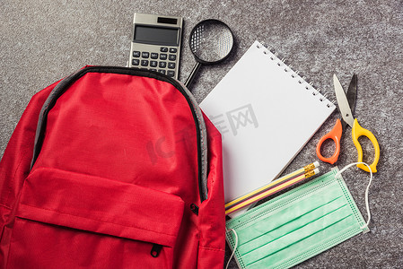 学校班级摄影照片_带面罩保护的桌上红色书包背包