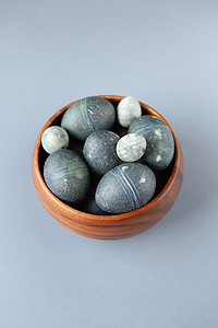 用天然芙蓉染料创造性地绘制鸡肉和鹌鹑复活节彩蛋，看起来像灰色背景碗中的海石，复制空间。