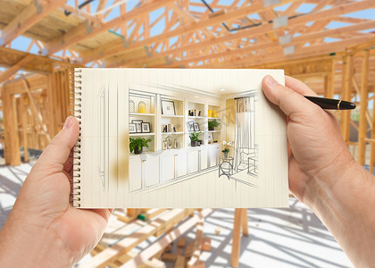 手拿笔和纸垫，内置架子和橱柜在房屋建筑框架内。