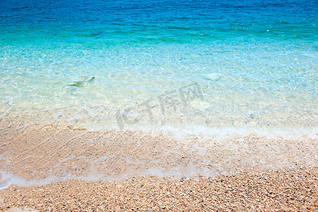 海水翻滚摄影照片_清澈的海水在石岸上翻滚