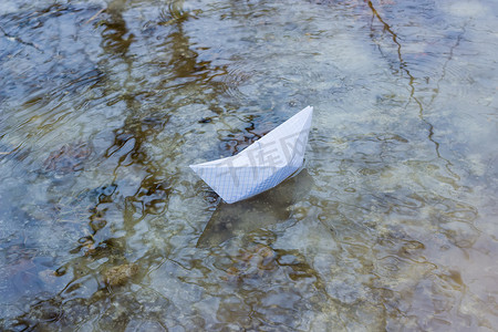 玩具帆船摄影照片_融水水坑中的纸船