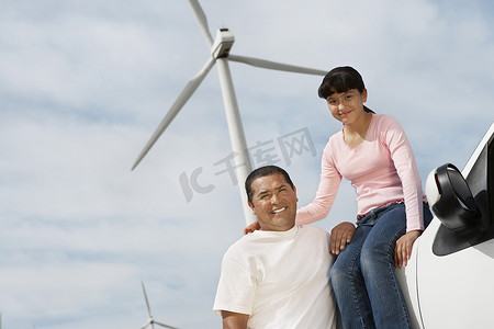 小女孩坐在车上，父亲站在风电场旁边的画像