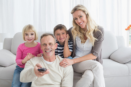 微笑的家人坐在沙发上换电视频道