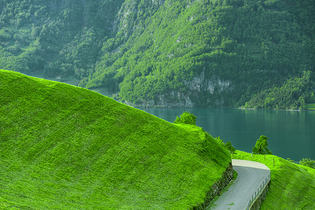 绿山摄影照片_在绿色小山的道路有湖和山的在背景中