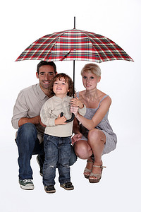 伞下的男孩摄影照片_庇护在伞下的年轻家庭