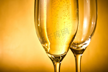 一杯香槟和一杯空的，里面有金色的气泡和文字空间