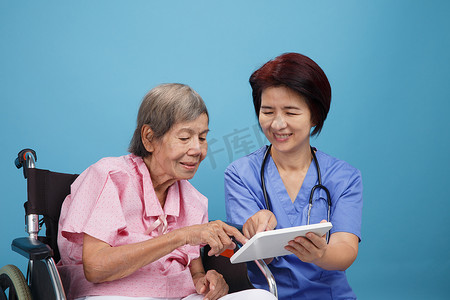 亚洲护士与坐在轮椅上的老年女病人交谈