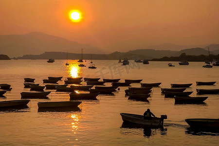 湖上有太阳的渔船剪影和太阳下的山