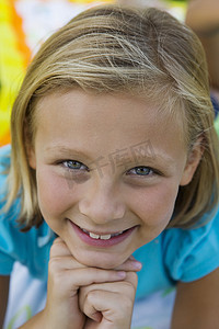 一个美丽的小女孩的特写肖像，双手放在下巴上微笑