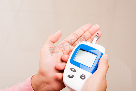 激光血糖仪摄影照片_测量葡萄糖测试水平的妇女用手指上的血液检查