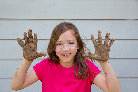 快乐的小女孩用脏手微笑着玩泥巴