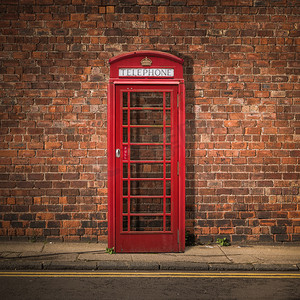 电话亭人摄影照片_红砖墙上的英国电话亭