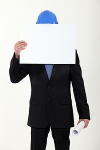 建筑施工海报摄影照片_建筑商人用空白海报遮住脸