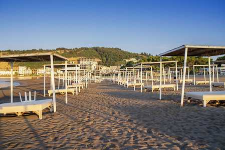 海边的太阳伞和沙滩床。海边有茅草屋顶的太阳床。