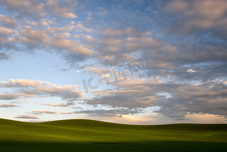 月亮云彩摄影照片_美国华盛顿州惠特曼县春天日落时起伏的丘陵、云彩和月亮