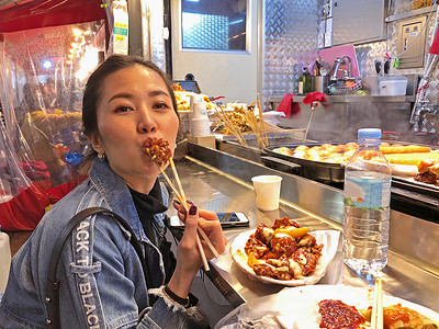 在 S 吃脆脆的韩国炸鸡街头食品的年轻女人