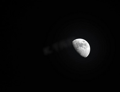 黄色月光摄影照片_夜间在晴朗的天空中看到的黄色半月的极端变焦远摄照片