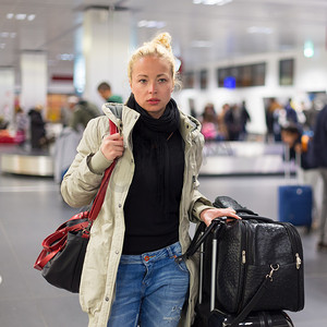 女旅客在机场航站楼运送行李。