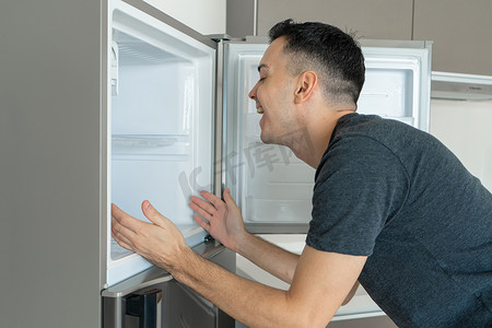 在炎热的天气里，这家伙把头放在冰箱里降温。