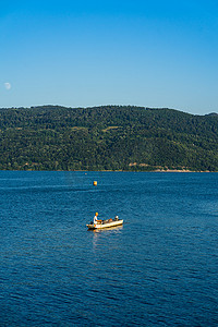 钓鱼船摄影照片_阳光明媚的日子里，在多瑙河上放松和钓鱼的人