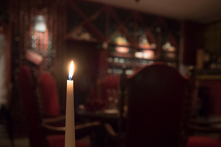 酒厂里的蜡烛，背景中模糊的红色椅子和一瓶酒