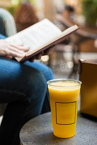 在咖啡馆里用橙色鸡尾酒看书的女人