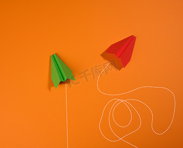 橙色背景中两架运动轨迹不同的纸飞机