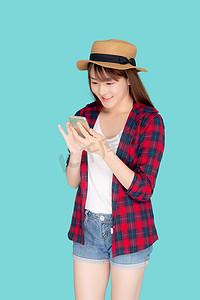 美丽的年轻亚洲女性在度假时触摸智能手机，与世隔绝在蓝色背景下，亚洲女孩在夏季旅行、旅行或教育概念中在智能手机上聊天或聊天。