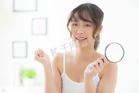 美丽的亚洲年轻女性对粉刺皮肤的放大感到满意，