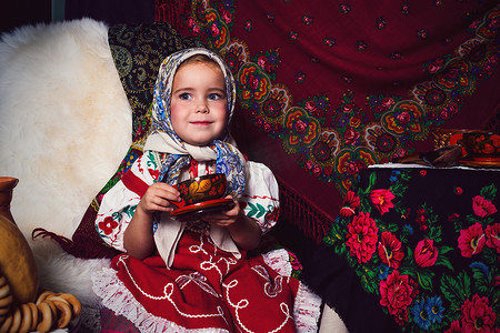 少数民族矢量傈僳摄影照片_在茶会上穿着民族服饰的可爱蹒跚学步的女孩