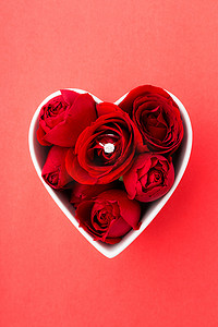 心形玫瑰花瓣摄影照片_红色玫瑰和钻石戒指在红色 b 上的心形碗内
