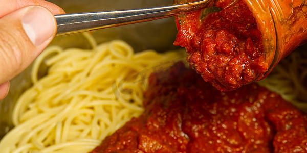 锅里的面条摄影照片_在锅里的意大利面条上加入肉酱。