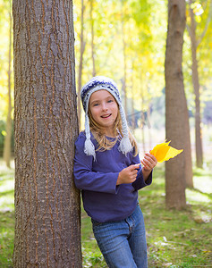 秋杨树林中的小女孩手里拿着黄落叶