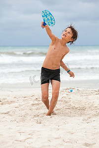 夏天在沙滩上玩沙滩球的快乐小孩男孩