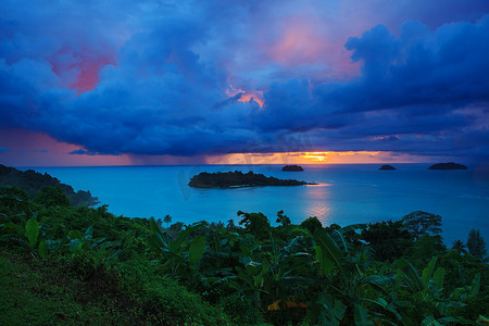 夕阳落下摄影照片_trat p的象岛后面下着雨云和太阳落下的天空