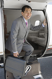 全套西装摄影照片_快乐的日本商人在机场从私人飞机上下来
