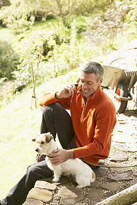 男子在户外与狗一起玩手机，同时从 Garde 休息