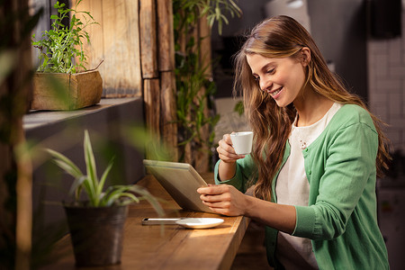 微笑的女人喝咖啡和使用平板电脑