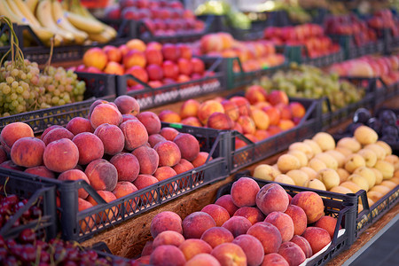 水果集市桃子葡萄杏子成熟多汁躺在塑料盒陈列柜里。