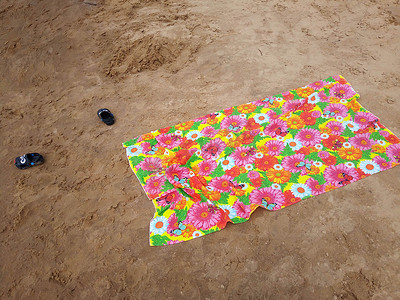 湿沙滩上的多色沙滩巾和儿童沙滩拖鞋