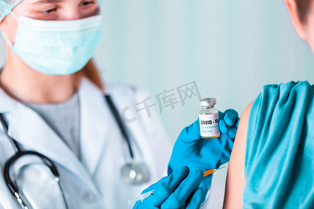 注射瓶摄影照片_身着制服和手套的医生或护士在实验室制作带有 COVID-19 冠状病毒疫苗标签的注射疫苗瓶