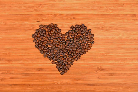 在竹木背景的心形的咖啡豆