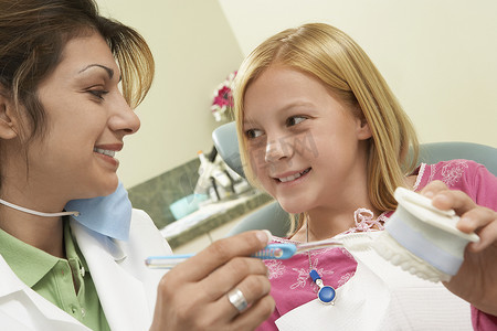 牙科教学摄影照片_牙医的特写，展示如何用模型下巴和牙刷清洁牙齿