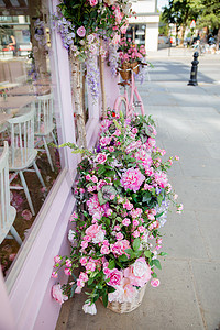 烧烤店门头摄影照片_粉色蛋糕店橱窗外人造花的肖像